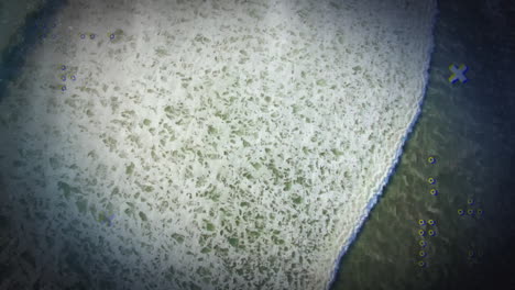 ocean waves meeting sandy beach with colorful digital animation overlay