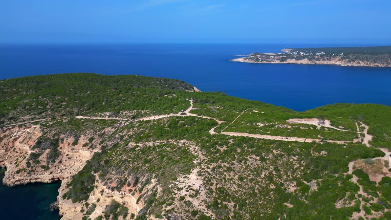 luxury villa in Ibiza, Spain, overlooking a picturesque bay with turquoise water and boats sailing on a sunny summer day. Dramatic aerial view flight panorama overview drone