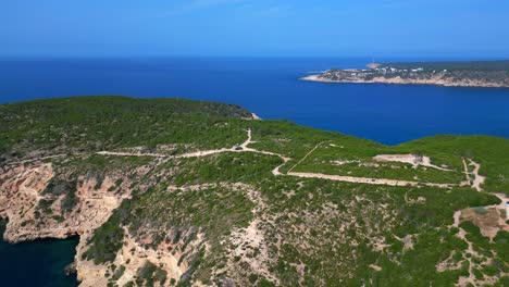 luxury villa in ibiza, spain, overlooking a picturesque bay with turquoise water and boats sailing on a sunny summer day. dramatic aerial view flight panorama overview drone