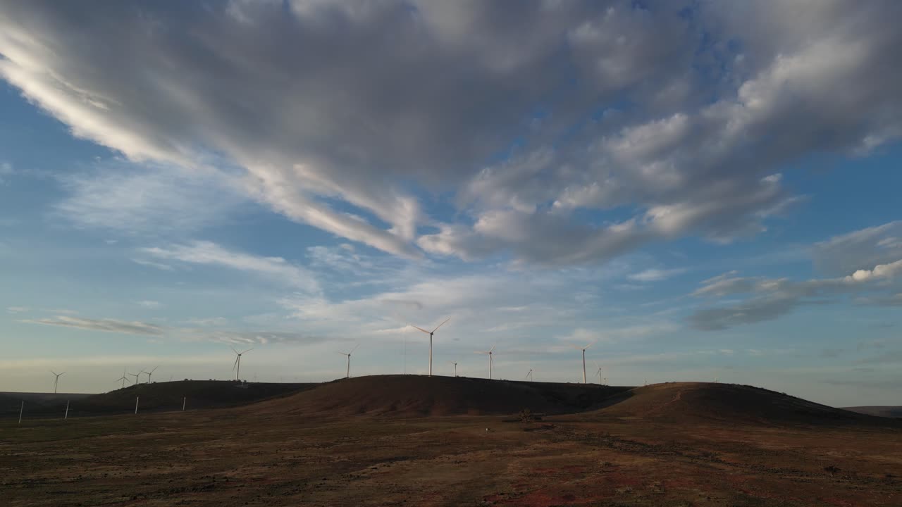 Wind Farm on Rolling Hills Under a Cloudy Sky