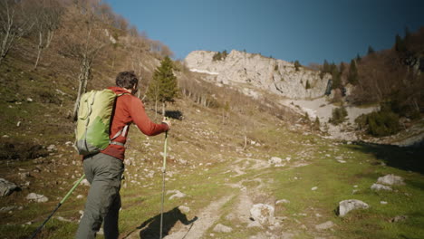 Seguimiento-De-Cámara-Desde-Detrás-De-Un-Excursionista-Caminando-Por-Un-Sendero-En-Una-Montaña,-Tees-Deciduoud-Sin-Hojas,-Cielo-Despejado