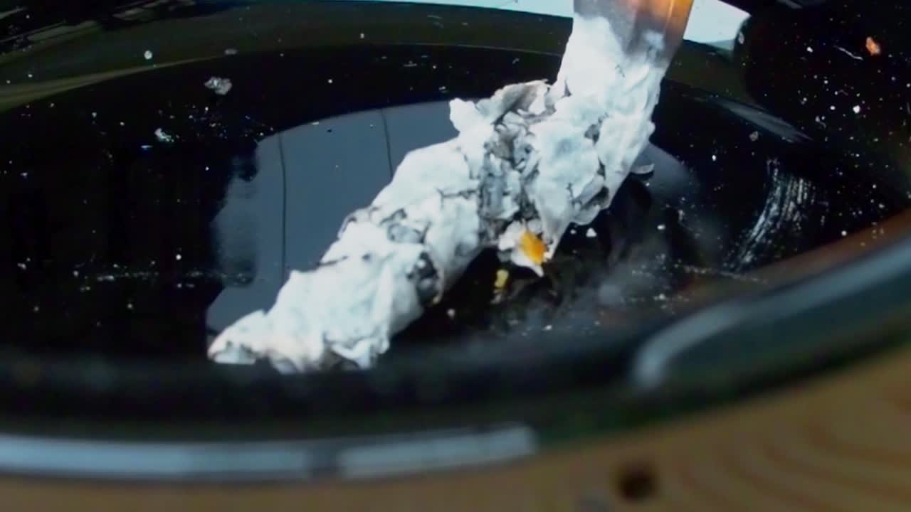 Accumulated cigarette ashes in a black ashtray, addiction and bad for health