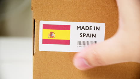 hands applying made in spain flag label on a shipping cardboard box with products