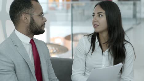 mujer de negocios sosteniendo papeles y hablando con un colega