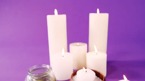 Sea-salt-in-wooden-bowl,-oil-and-candles-on-table