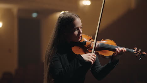 young student violinist is playing violin in music hall portrait of woman fiddler in symphonic orchestra