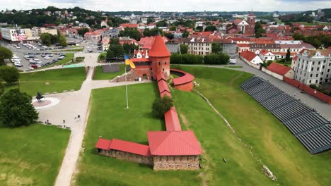 tomada de avión no tripulado del histórico castillo de ladrillo rojo de kaunas con bandera ucraniana en el casco antiguo de kaunas, lituania, toma de paralaje