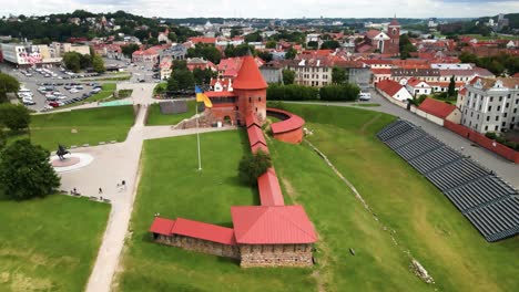 drone shot of the historic old red brick kaunas castle with ukrainian flag in kaunas old town, lithuania, parallax shot