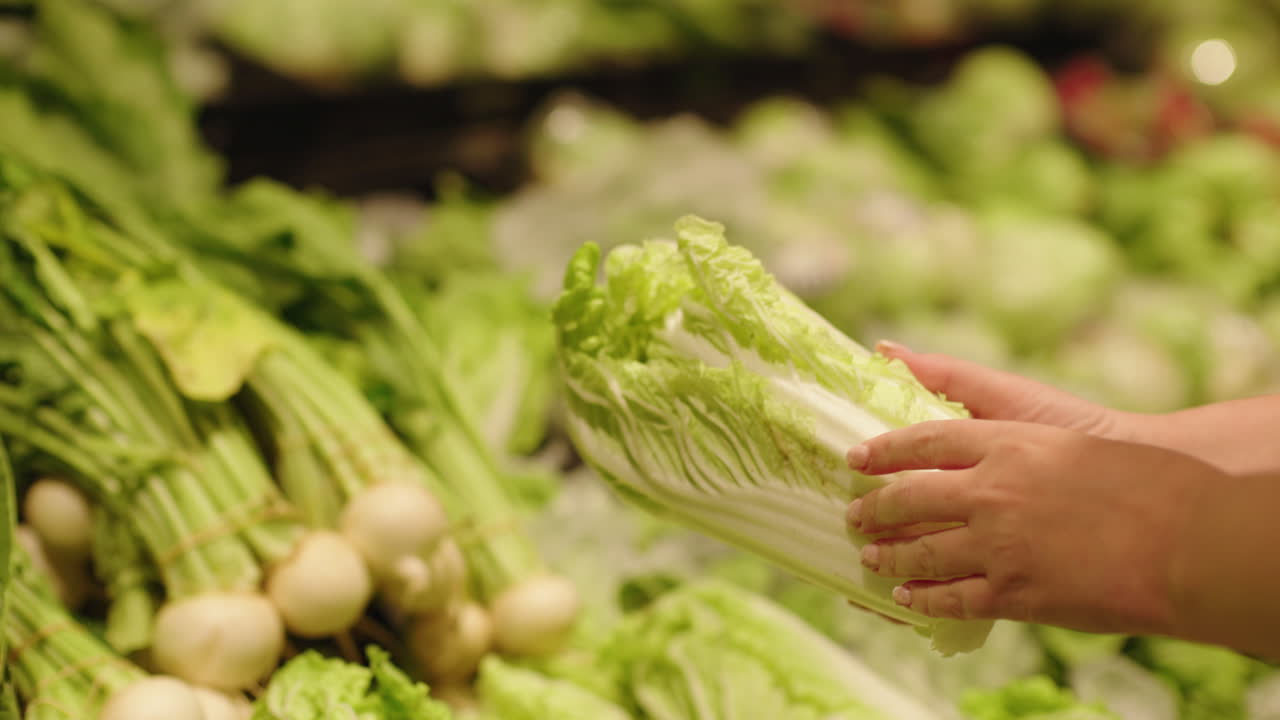 Woman choosing fresh napa cabbage in supermarket vegetable section with organic leafy greens and healthy produce