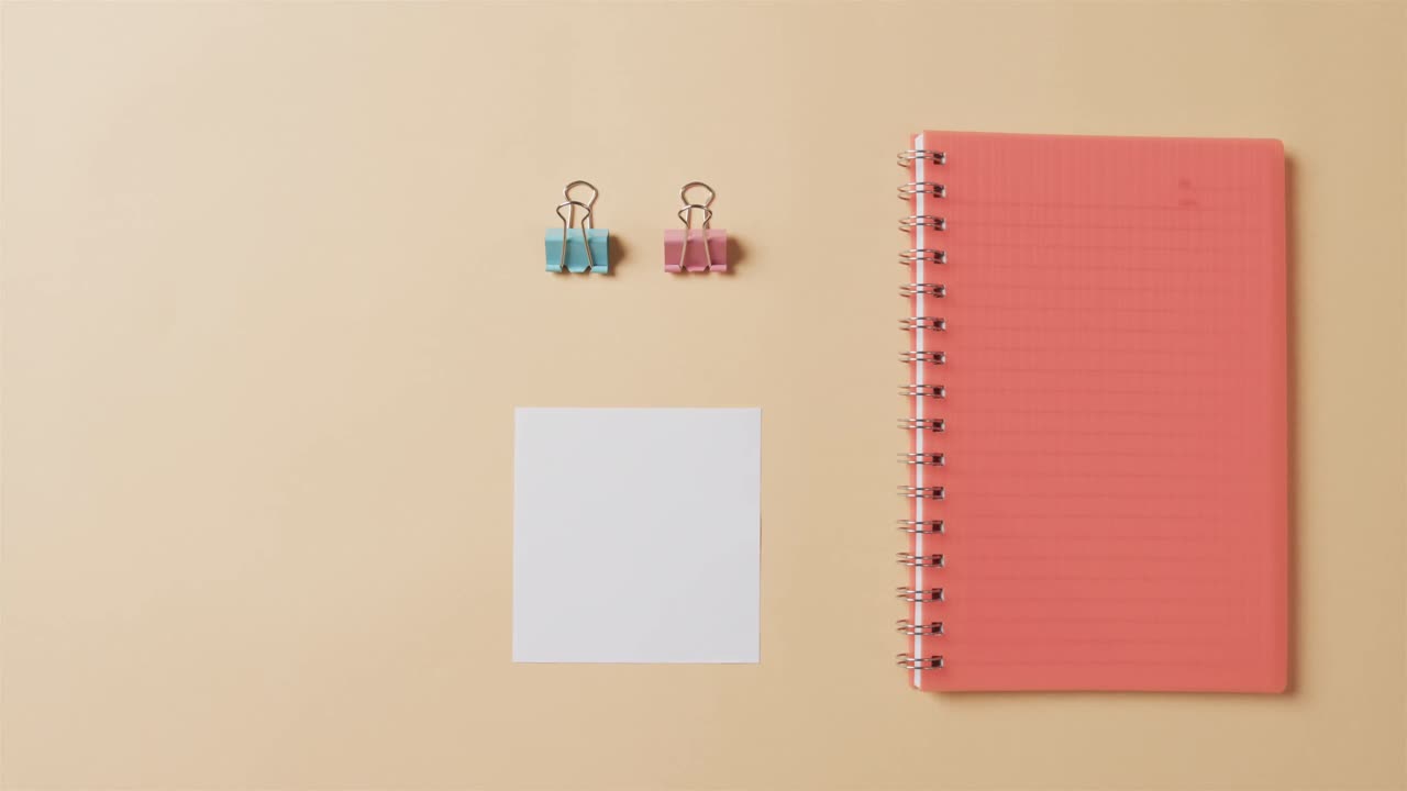 Overhead view of red notebook and school stationery arranged on beige background, in slow motion