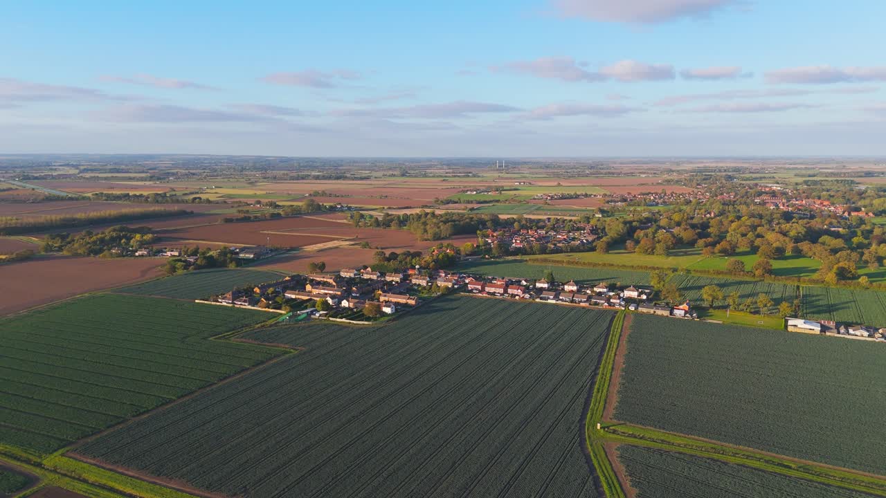 Rural Agricultural footage of Lincolnshire farmland with crops growing in patchwork fields on the east coast of Britain. Acres of farmland surrounded by small rural village home