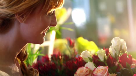 beautiful female florist smelling pink rose