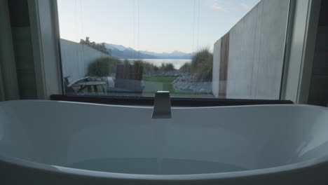 Slow-motion-footage-of-chic,-white-bath-tub-in-front-of-tall-window