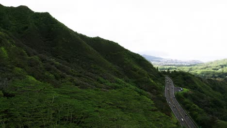 Drone-shot-of-cars-driving-along-Hawaii's-remote-Pali-Highway