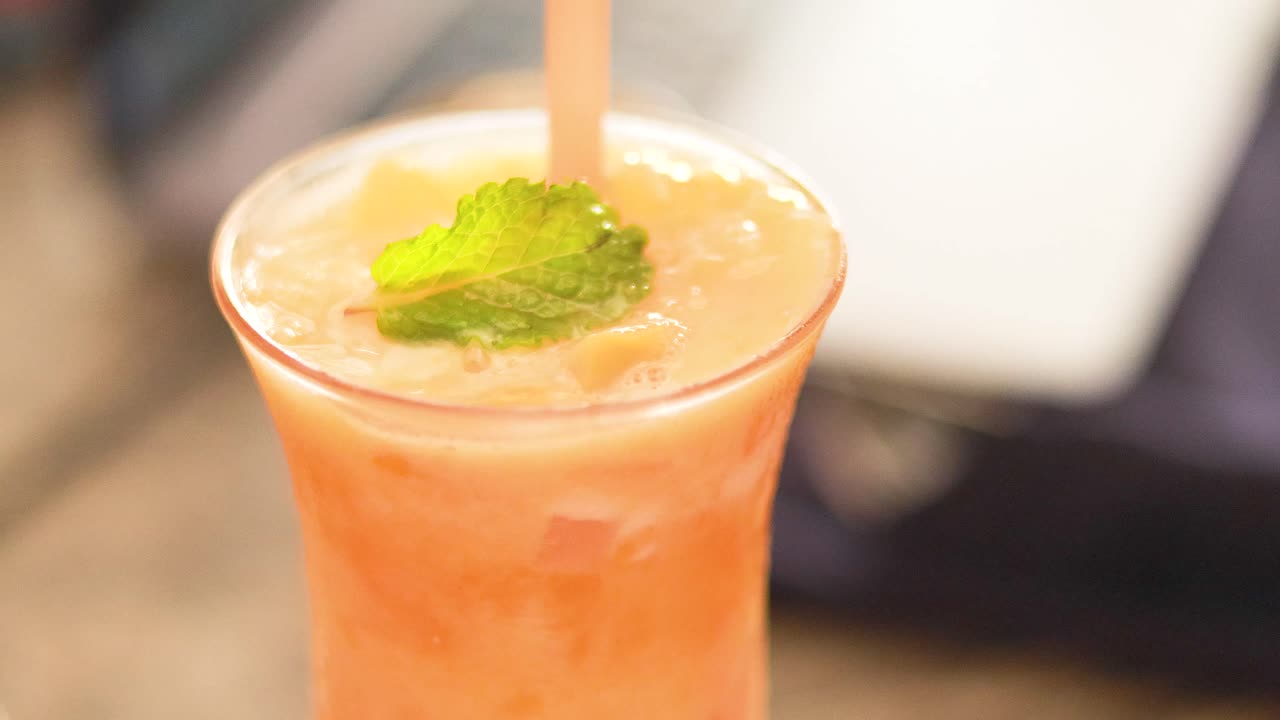 신선한 망고 주스 음료를 고 잔에 민트 잎으로 장식합니다.
