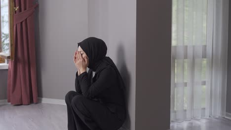 depressed young muslim woman crying while leaning against the wall.