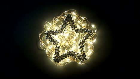 Loop video greetings card with Merry Christmas writing animation on glowing yellow garland on metal bell decoration on dark background