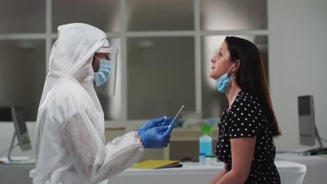 medical worker in protective clothing taking swab test from female patient