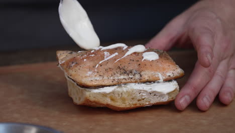 chef adding mayonnaise on top of sandwich sprinkled with pepper