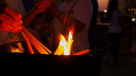 persons lighting candles as a religious beliefs of the buddhism tradition - close up shot