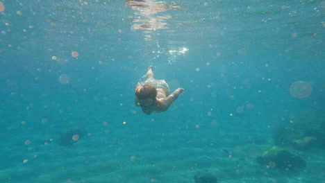 slow motion - teenager swims underwater in the sea