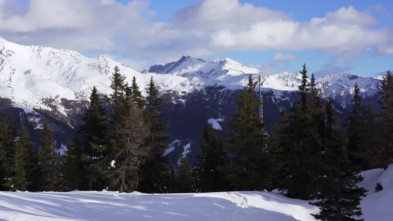 radio mast partly hidden behind pine trees on snow cover mountain in the Italian alps near the border with Austria