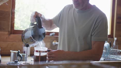 senior caucasian man preparing pot of coffee in kitchen