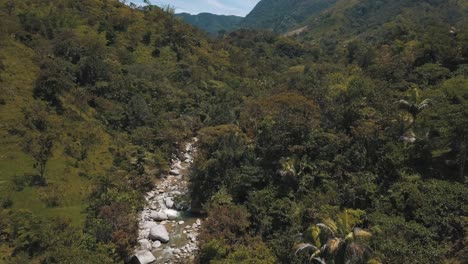 Drone-aerial-rising-shot-in-the-forest-and-a-river-with-rocks-in-Medellin,-Colombia