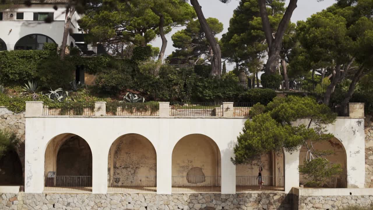 Giovane ragazza cammina attraverso il passaggio di un'antica hacienda in una scena magica della bellezza della Costa Brava.