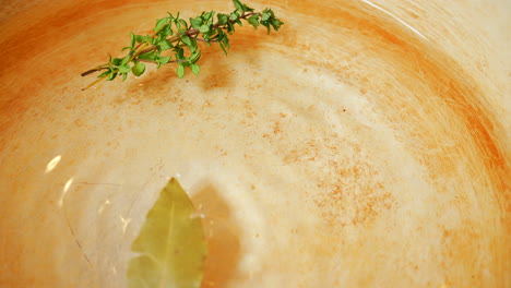 agua condimentada para hervir arroz con una ramita de romero y una hoja de laurel - dejando caer la hoja de laurel en una olla de agua a cámara lenta