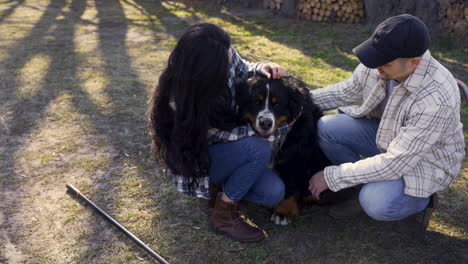 casal caucasiano acariciando seu cão no campo