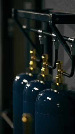 industrial setup featuring blue gas cylinders in a dimly lit environment