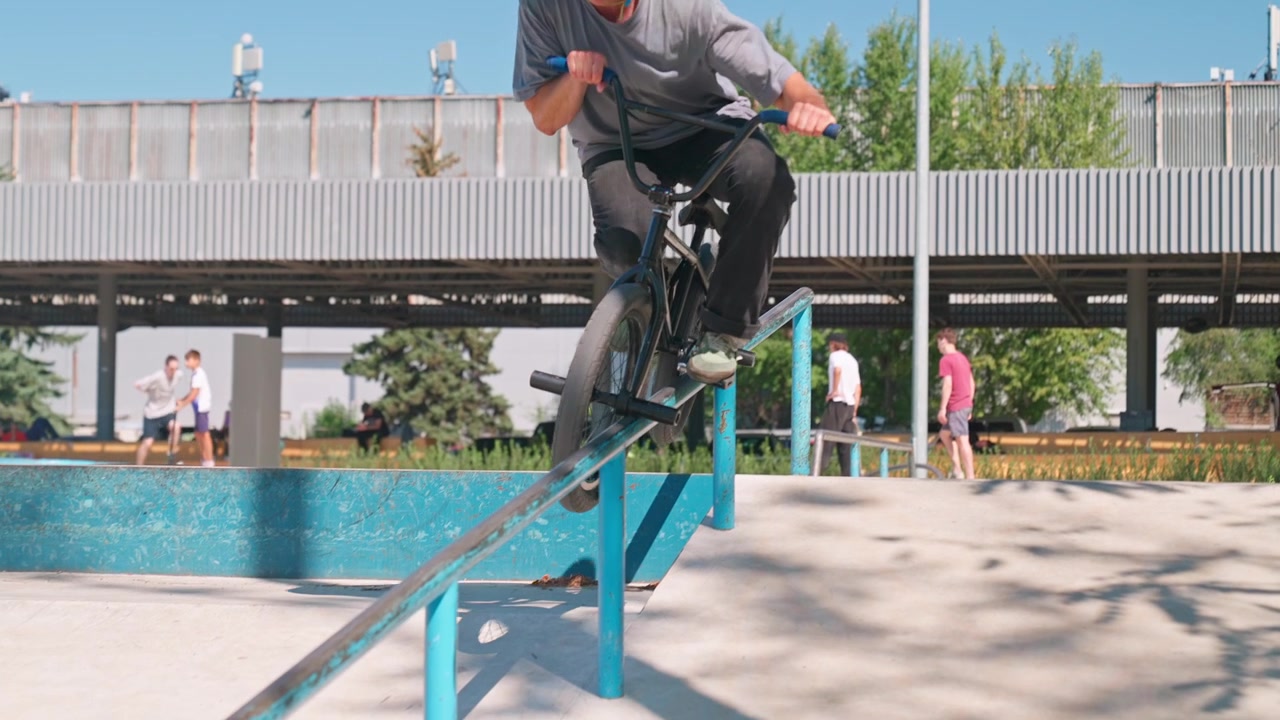 Ragazzo in BMX che fa grinding su un rail nello skatepark