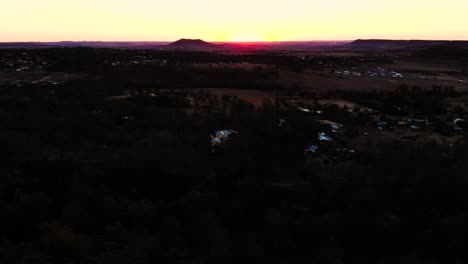 A-drone-flies-over-a-small-dirt-pile-to-reveal-a-beautiful-sunset-bathing-a-valley-in-its-warm-afternoon-glow