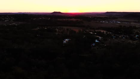 un dron vuela sobre un pequeño montón de tierra para revelar una hermosa puesta de sol que baña un valle en su cálido resplandor vespertino
