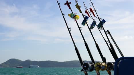 las varas de pesca se balancean suavemente en un barco en phuket, capturando un paisaje marino sereno con islas lejanas bajo un cielo despejado