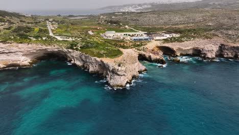 aerial view of a black 4x4 atop the rugged cliffs of ras tanit, with the wild maltese coastline, sea caves, and crystal-clear waters setting the scene for exploration and adventure.