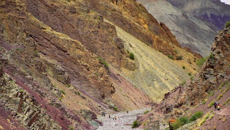 tilt down shot as people, backpackers wondering on in the markha valley india, between high mountains