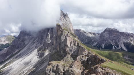 persona de pie en el borde de la cima de la montaña después de caminar por la cordillera de seceda en italia - vista espectacular al valle durante el día de verano con nubes en el cielo