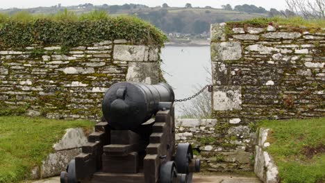 placement d'un canon dans une ancienne défense maritime militaire avec un voilier en arrière-plan