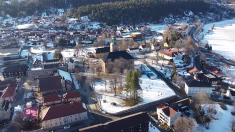 Antena-De-La-Ciudad-De-Kongsberg-Volando-Hacia-El-Suroeste-Hacia-La-Iglesia-De-Kongsberg---Soleada-Mañana-De-Invierno-Cerca-Del-Río-Numedal-A-La-Derecha