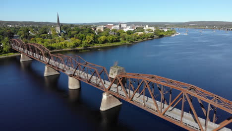 aerial: flying past walking bridge on saint john river in fredericton, new brunswick