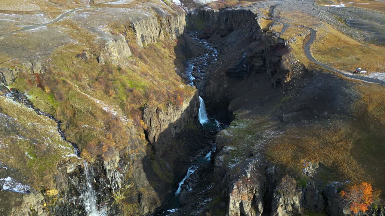 cascadas en el cañón rocoso de islandia en la base de una montaña nevada, aérea