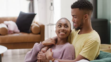 happy african american couple talking and hugging on sofa