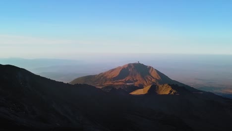 aerial of the beautiful pico de orizaba volcano with a view of the large millimeter telescope in mexico at sunrise