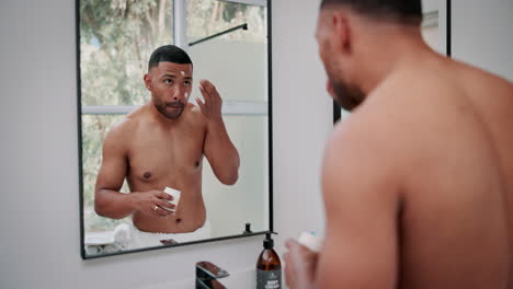 man applying cream to his face in bathroom mirror