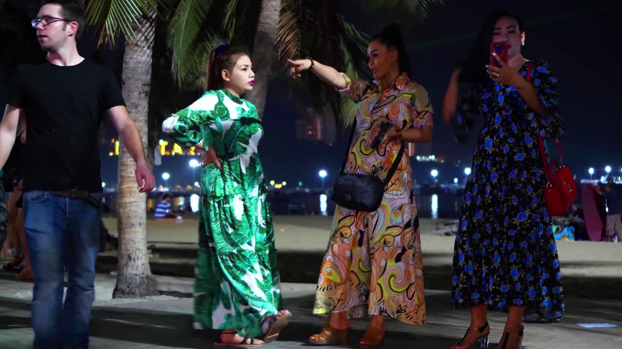A group of three prostitutes in colorful dresses attract customers