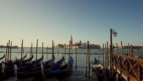 Gondolas,-typical-boats-from-Venice,-moving-on-the-water-in-the-lagoon-near-the-main-square