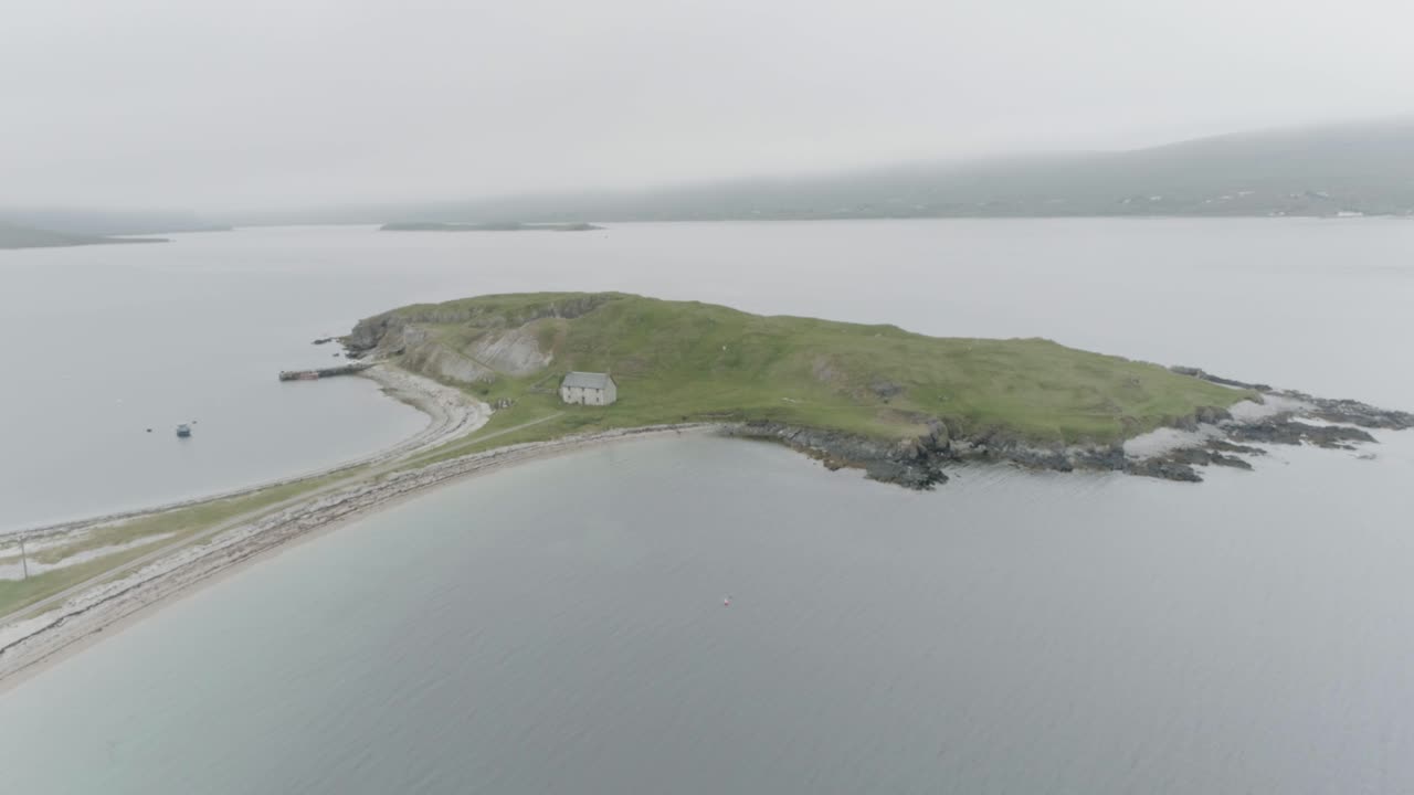 Slow wide drone reveal of a small island connected to the mainland with a single house on it outside Durness on the North Coast of Scotland