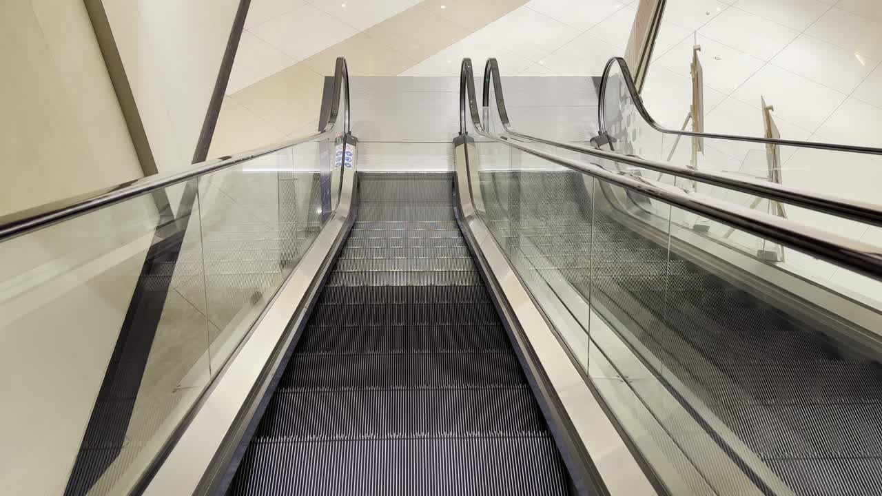 A point-of-view shot of descending an escalator, with a safety instruction poster visible on the side
